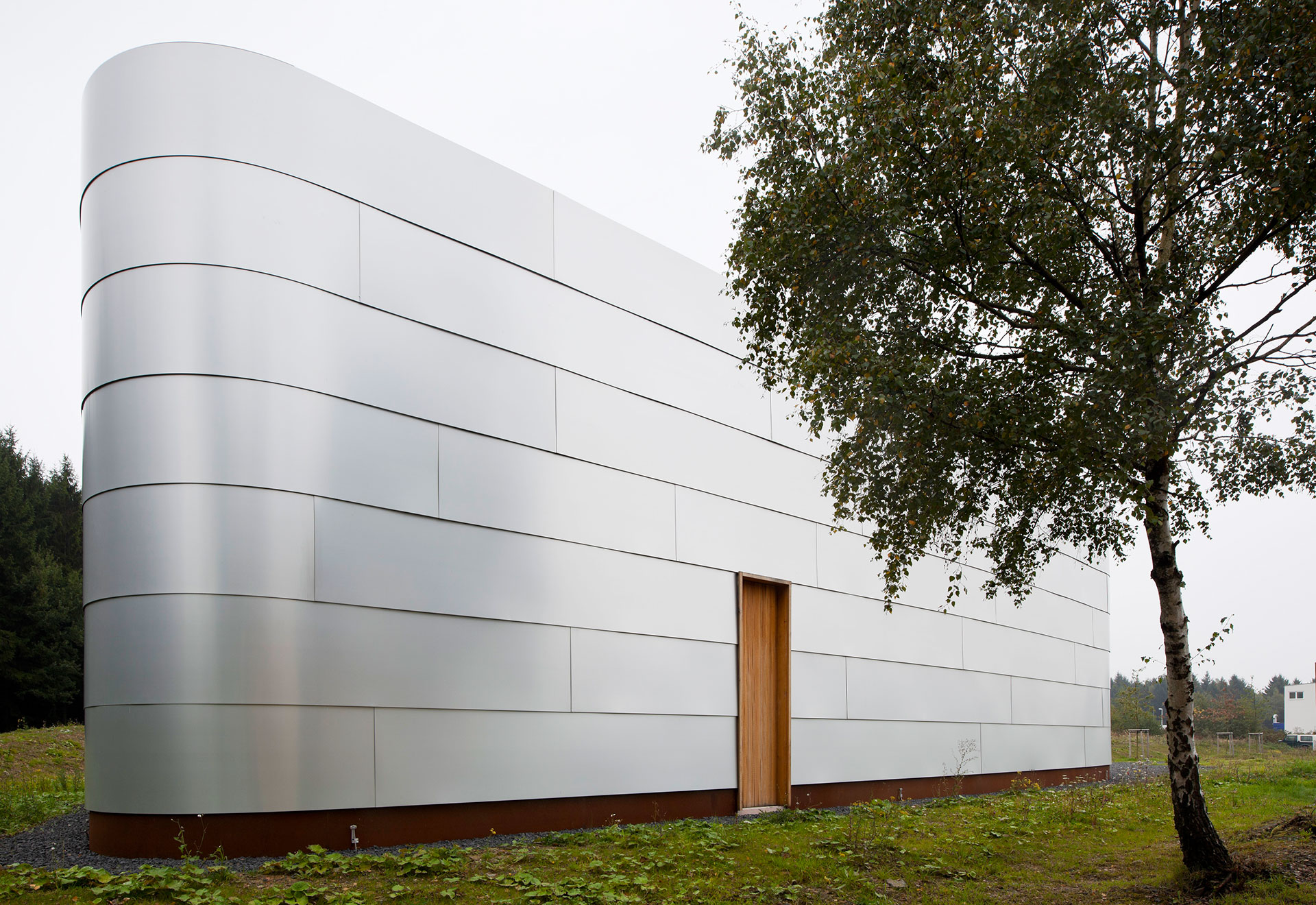 Schaulager-Architektur mit Aluminiumfassade, gerundeten Ecken, Holztür