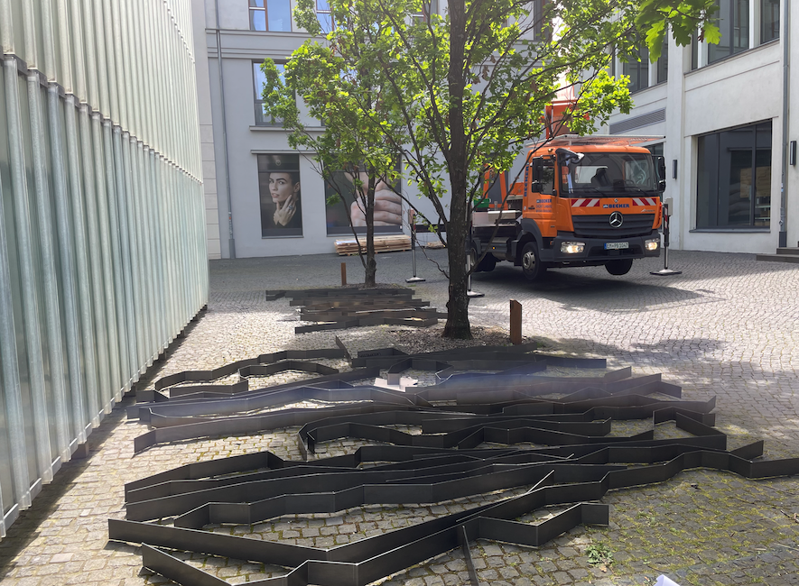 Erdliner liegen vor dem Mdbk; Baustellenfahrzeug im Hintergrund